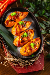 Verical top view image of mussels with cheese filling decorated with tobico and teriyaki at restaurant table background.