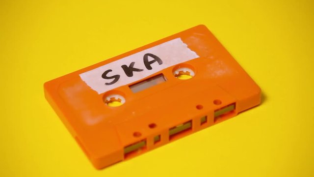 Writing the text Ska on the rough label of a vintage cassette tape (obsolete music technology). Colorful scene.
