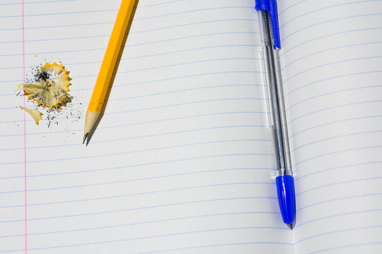 Photo of a fragment of a notebook in a line on which pen, pencil and shavings from a pencil lay