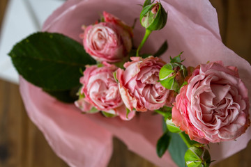 a bouquet of roses in a vase with envelope on wooden background
