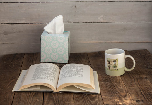 a cup with cafe an open book and a box with napkins