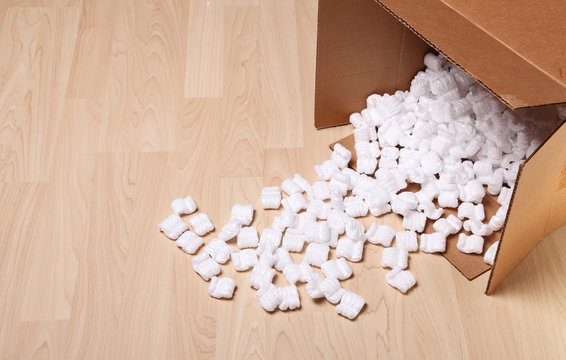 Open cardboard box with packing peanuts in the box and on the floor