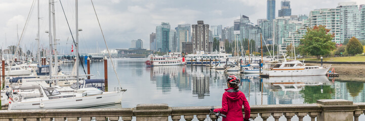 Vancouver woman at city skyline wearing helmet biking in harbour front of urban background panorama...