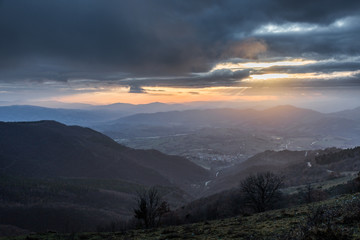 Sunrays coming over a valley in Umbria (Italy) with some plants in the foreground