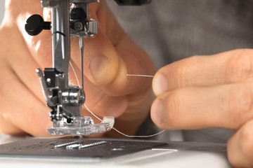 hands fill the thread in the sewing machine