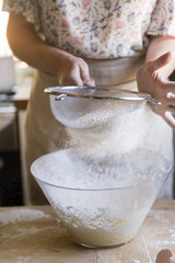 Woman sieving flour into a bowl