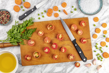 Prep time, or mise en place. An overhead photo of a professional chef's knife, shot from above on a cutting board, with chopped vegetables and spices, on a marble cooking surface © laplateresca