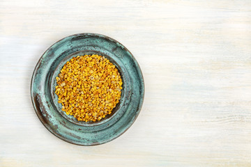 An overhead photo of pollen, shot from above on a light background with a place for text