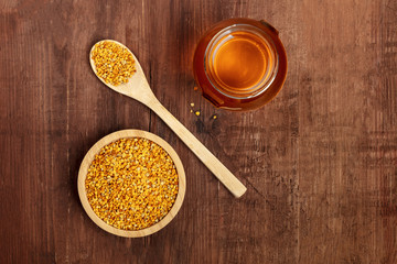 Healthy organic food. An overhead photo of pollen, a jar of honey, and a wooden spoon, shot from above on a dark rustic background with a place for text