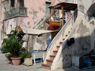 streetview of a facade with stairs and a boat in the harbor of Procida