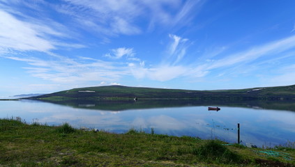 A boat in the north bay in summer morning with reflection of sky on water surface.