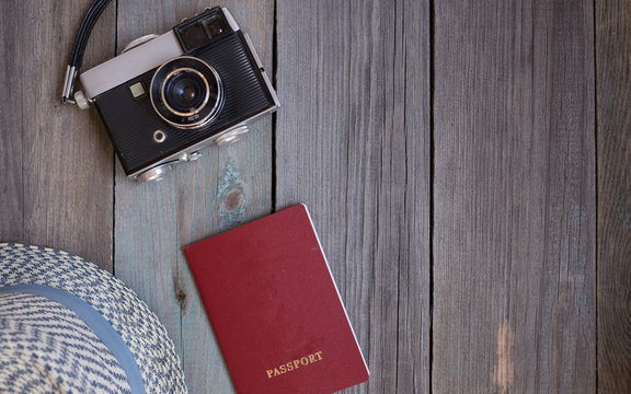 A passport, an vintage camera, a hat on wooden background