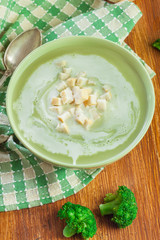 Broccoli cream soup in green bowl served with croutons