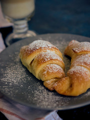 A cup of fresh coffee with croissants on a dark blue background, selective focus