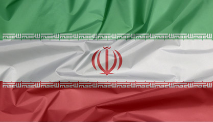 Fabric flag of Iran. Crease of Guinea Iranian flag background, green white and red color with National Emblem and the Takbir written in the Kufic script.