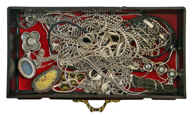 A young woman keeps her silver and gold rings  chains and bracelets in a dusty  mass production  box of dark red plastic. Isolated