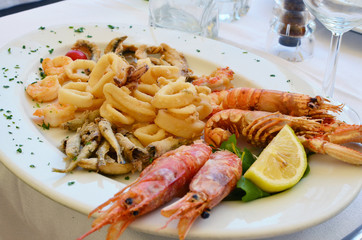 Shrimps squids and other seafood on a white ceramic plate in an Italian restaurant.
