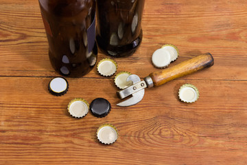 Old bottle opener among of bottle caps on rustic table