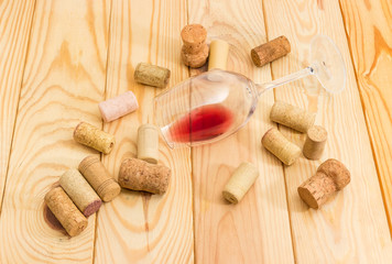 Glass with wine lying on its side among of corks