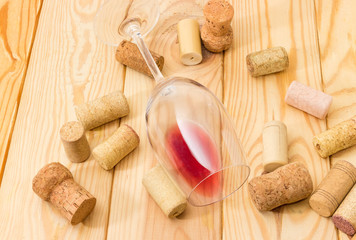 Glass with wine lying on its side among of corks