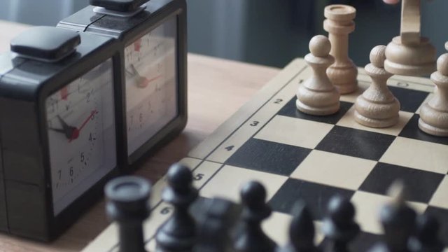 Chess. Man's hand making a move with white knight. then presses the clock button to stop the time