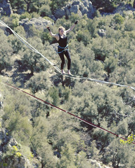 Highliner on a rope. Highline on a background of mountains. Extreme sport on the nature. Balancing on the sling. Equilibrium at altitude.