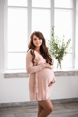 Beautiful smiling pregnant woman is holding belly