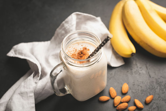 Banana smoothie or protein shake in drinking jar topped with cinnamon. Toned image, selective focus