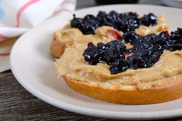 Toasts with peanut butter and berry jam on a plate on a wooden table. Nutritious breakfast. Traditional american food. Close up