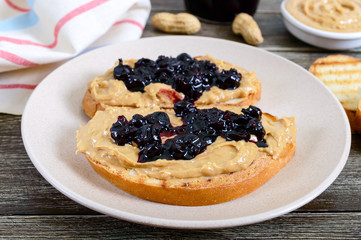 Toasts with peanut butter and berry jam on a plate on a wooden table. Nutritious breakfast. Traditional american food.