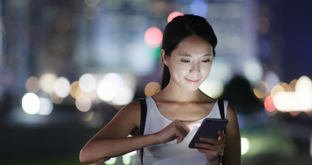 Woman look at mobile phone in city at night