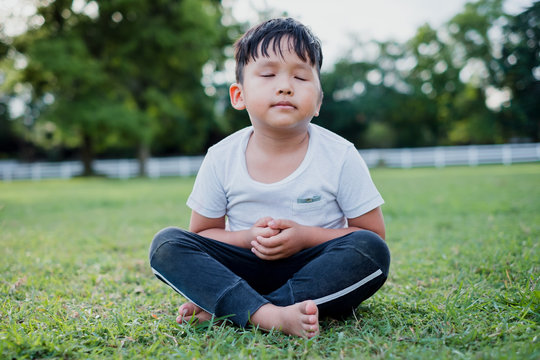Asian little boy meditation with peace and relax in the park outdoor.Meditation concept with copy space.