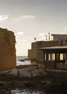 Man jumping to the water from the old city walls, Acre (Akko), Israel.