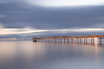 Old broken down wooden pier in Punta Arenas, old dock in Chile on the Pacific ocean. sunset