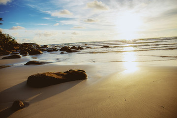 Rocks on sand beach with sunrise.