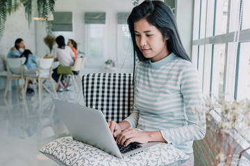 Portrait of  Woman using laptop computer and hands typing on keyboard in cafe.