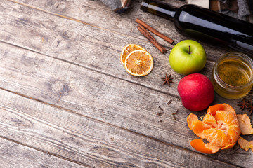 Ingredients for mulled wine: apples, tangerine, orange, spices, wine - on dark wooden background. Copy space.