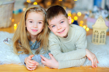 brother and sister lie on the floor amid a bright festive background