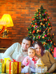 Fototapeta na wymiar happy family lies on the floor near the festive Christmas tree, near Christmas gifts