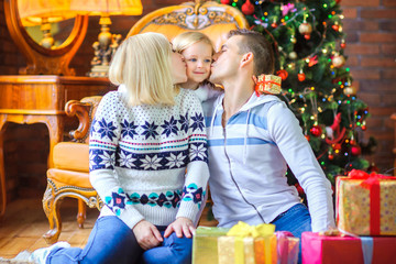 happy family sitting on the floor near the Christmas tree congratulates and gives each other gifts