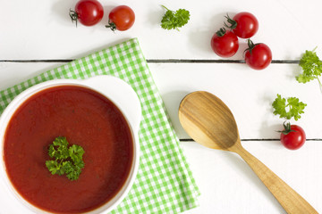 Creamy tomato soup with parsley and garlic on a blue kitchen table 
