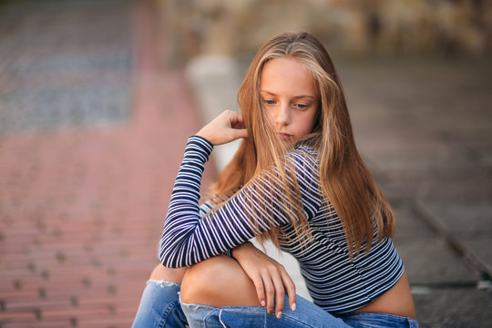young teenage poses to photographer. blonde girl in jeans and blouse