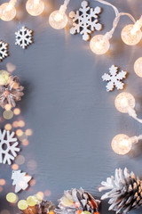 Winter background with Christmas lights, pine cones and decorations.