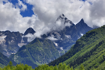 Fototapeta premium Peak of the mountain with glaciers against the background of clouds and sky. Caucasian ridge, Russia.