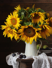 Obraz premium Still life with a bouquet of yellow sunflowers, plums and apples.