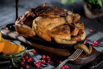 Grilled chicken with potatoes and cranberries on a wooden background.