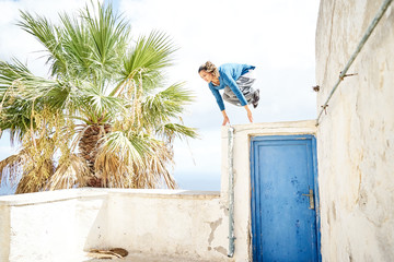Frau macht einen Parkour Sprung in einem Dorf in Santorin 