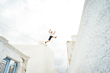 Mann macht Parkour und springt über die weißen Hausdächer in Santorin 