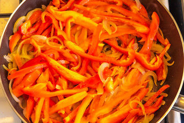 Pepper stew with onions in a pan close-up, top view