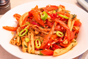 Italian food - Pasta with peppers and onions on a white plate close-up